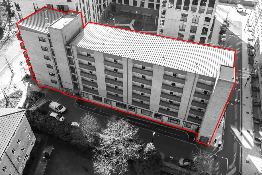 Black and white aerial photograph of an apartment building with its site boundary marked in red